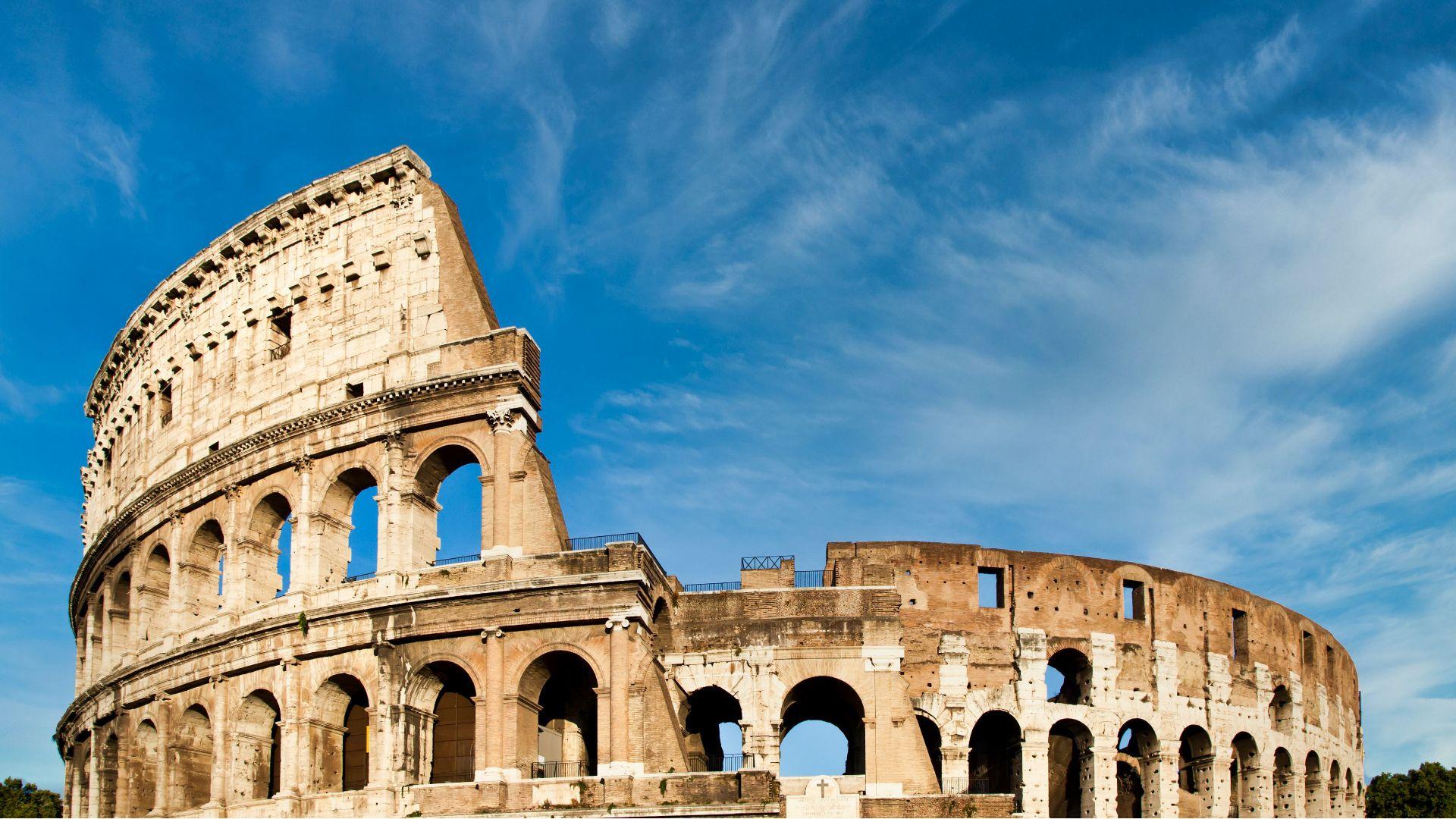 Il Colosseo di Roma, simbolo dell'antica architettura romana, sotto un cielo azzurro.