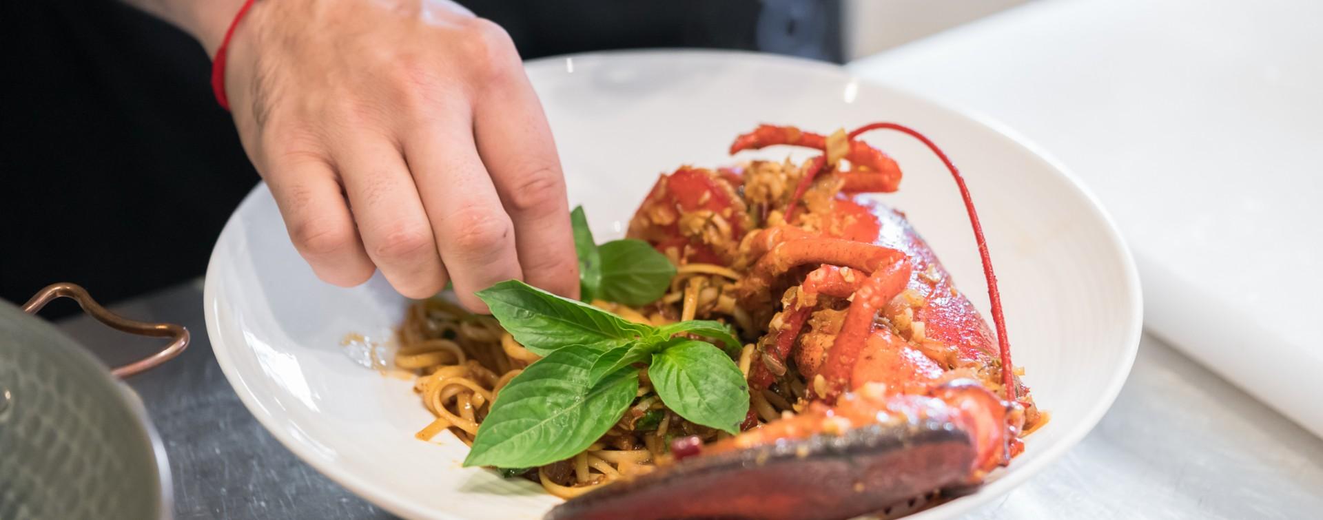 Piatto di spaghetti con aragosta e basilico, guarnito a mano.