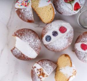 Ciambelle glassate con panna e frutta, decorate con zucchero a velo e granella.