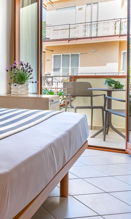 Coppia felice in accappatoio bianco, sorridente e abbracciata su un letto.