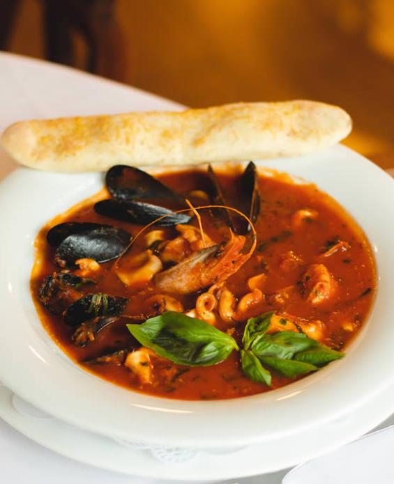Zuppa di mare con cozze, calamari e gamberi, servita con pane croccante.