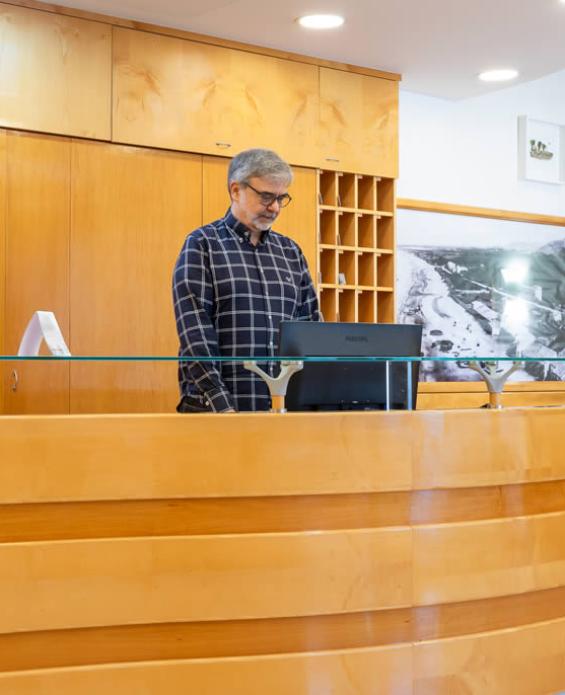 Reception di un hotel con arredi moderni e personale sorridente.