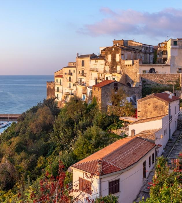 Case su una scogliera al tramonto con vista sul mare.
