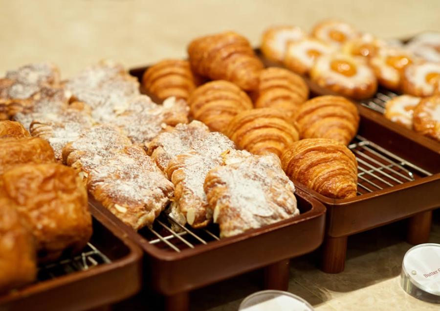 Vassoi di croissant e dolci glassati su un bancone di pasticceria.