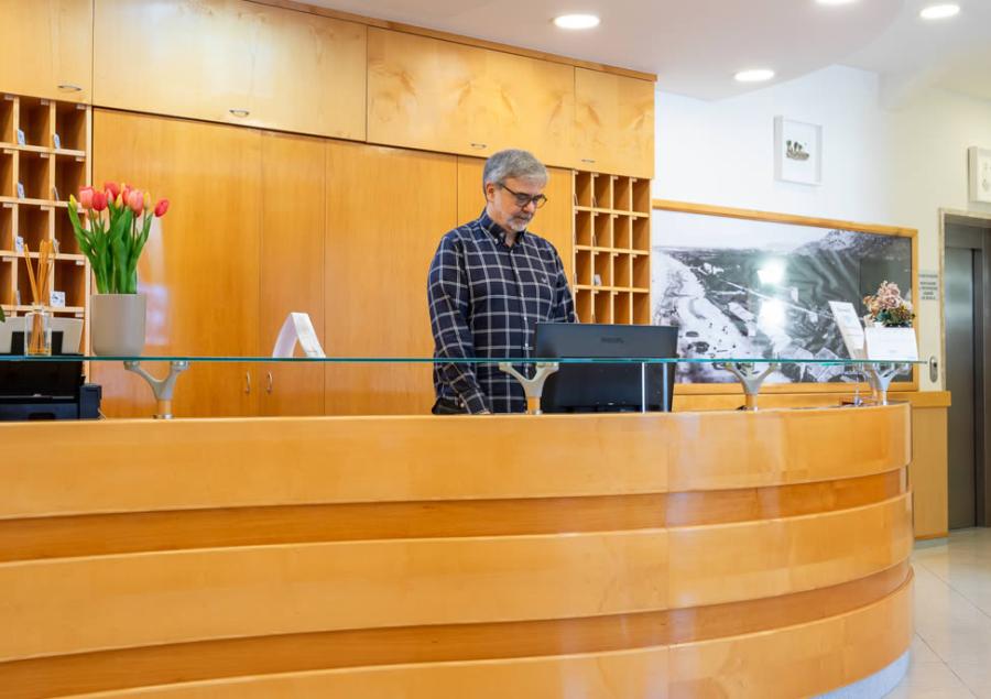 Reception di un hotel con arredi moderni e personale sorridente.