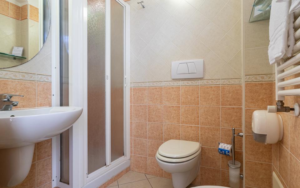 Bagno accogliente con doccia, lavabo e wc, piastrelle arancioni creano un'atmosfera calda.