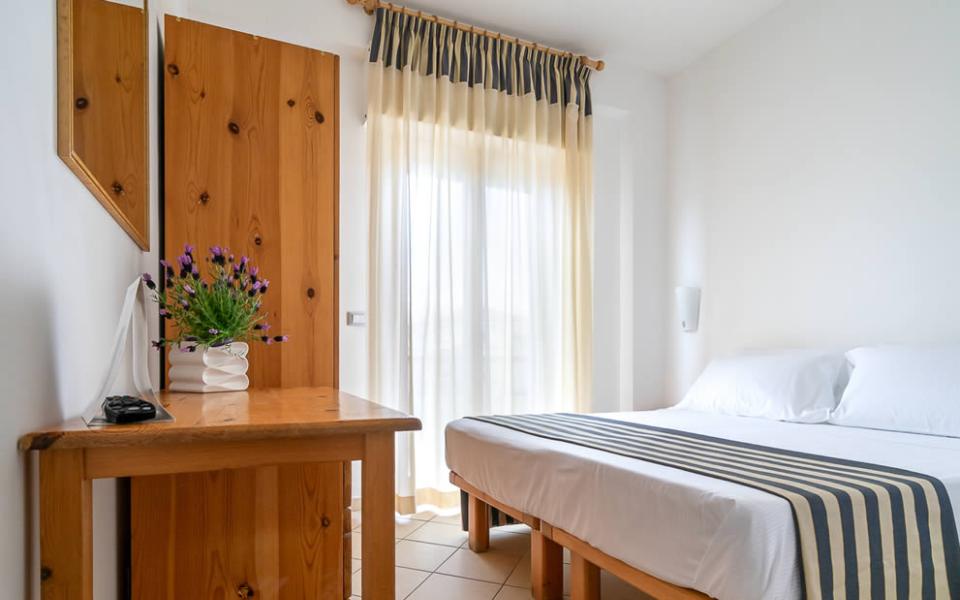 Camera d'albergo con letto matrimoniale, bagno privato e balcone con tavolo e sedie.