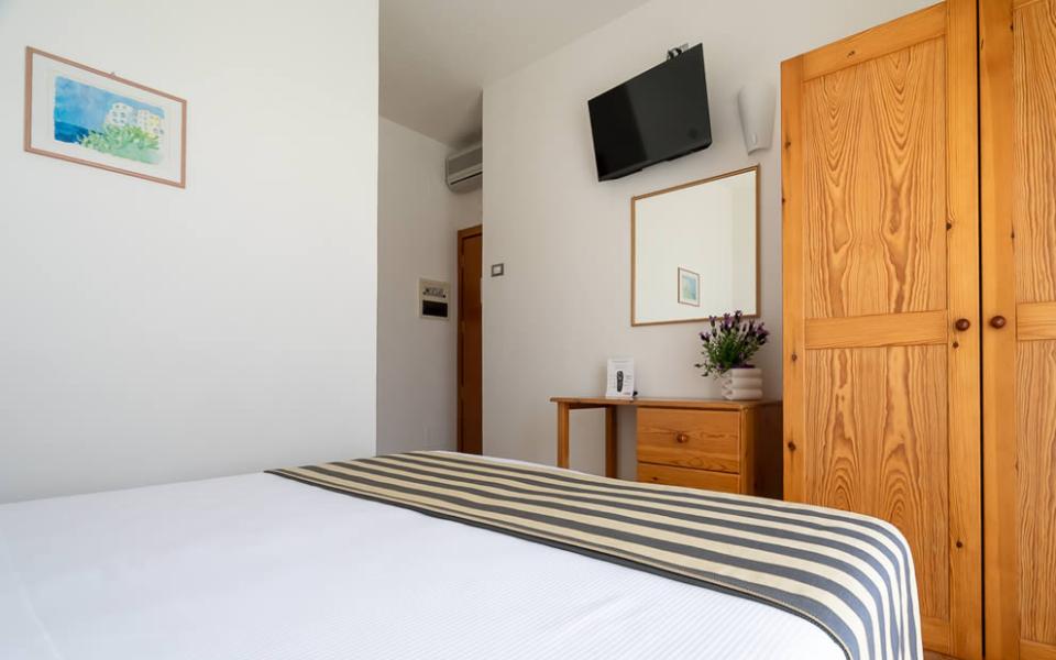 Camera con letto a righe, accappatoi, scrivania, e fiori decorativi.