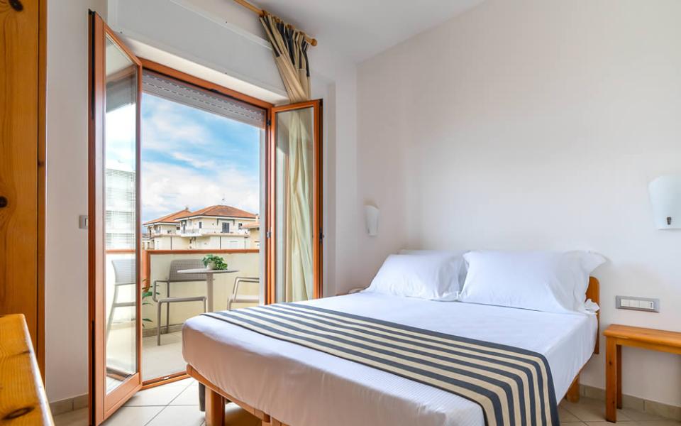 Camera d'albergo con bagno; letto a righe e accessori da bagno moderni.