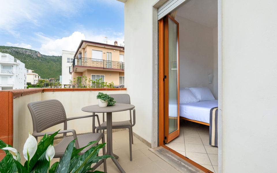 Balcone accogliente con tavolo, sedie e vista montagna. Interno luminoso e rilassante.